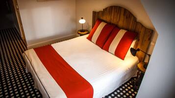 Una habitación de hotel con una cama, una mesita de noche, una lámpara y un piso a cuadros.