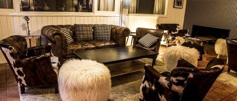 Ein gemütliches Wohnzimmer mit einem Ledersofa, passenden Sessel, einem flauschigen weißen Teppich und einem Fernseher.