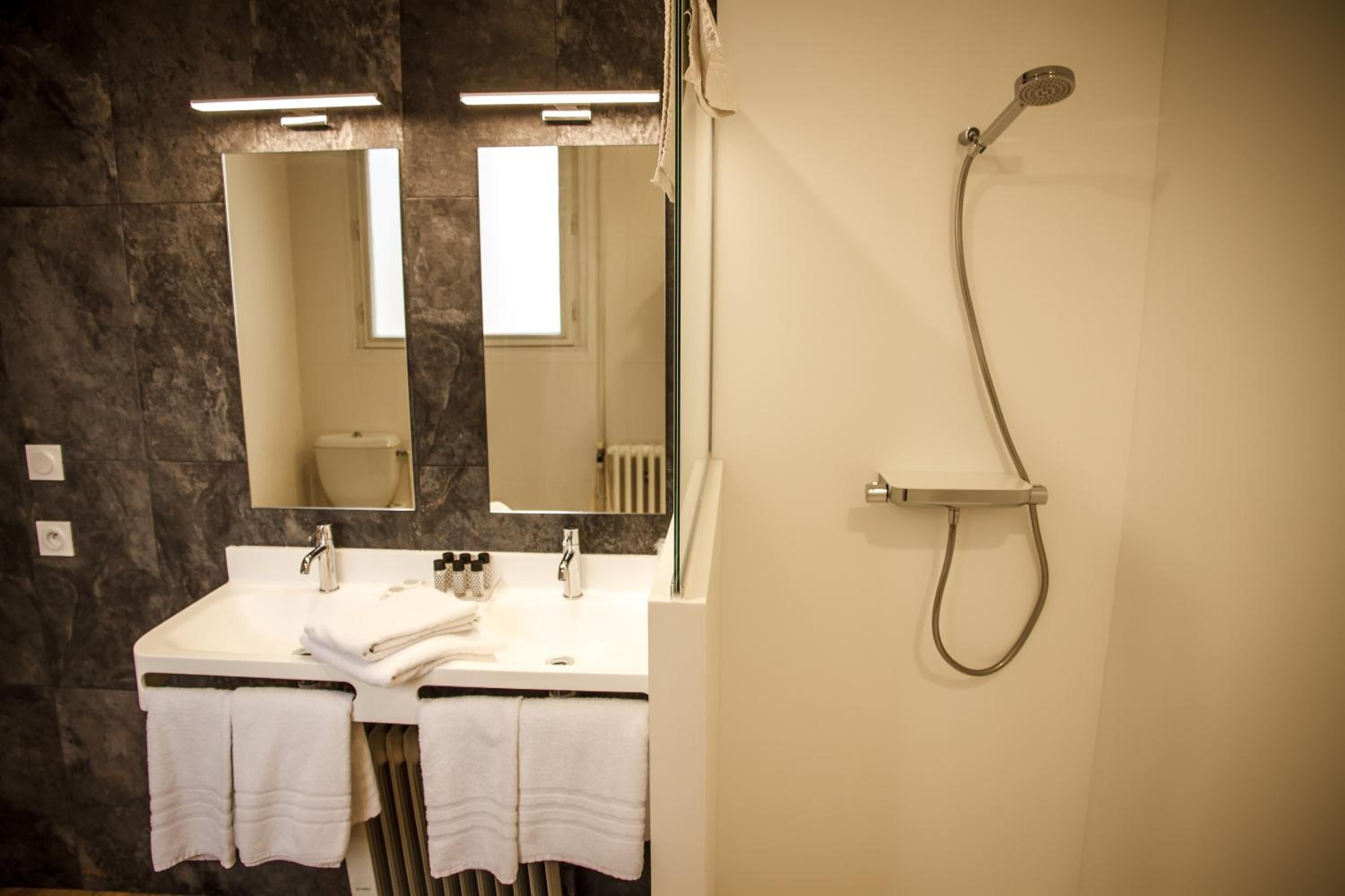 Une salle de bain avec deux lavabos, un miroir, une douche et des serviettes.