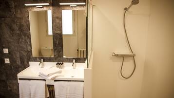 Een badkamer met twee wastafels, een spiegel, een douche en handdoeken.