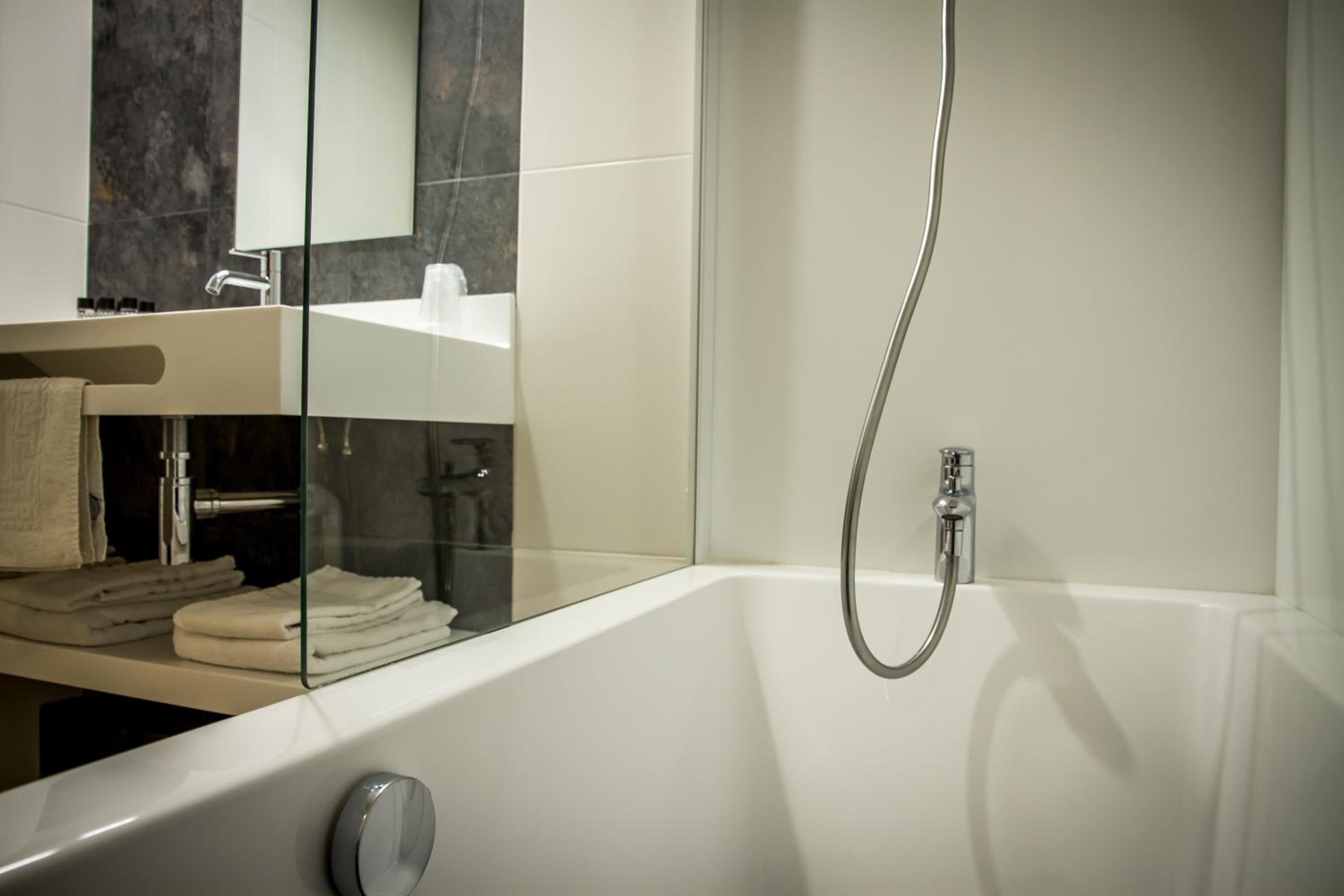 Une salle de bain moderne avec une douche à parois de verre, une baignoire blanche et un meuble-lavabo avec un miroir.