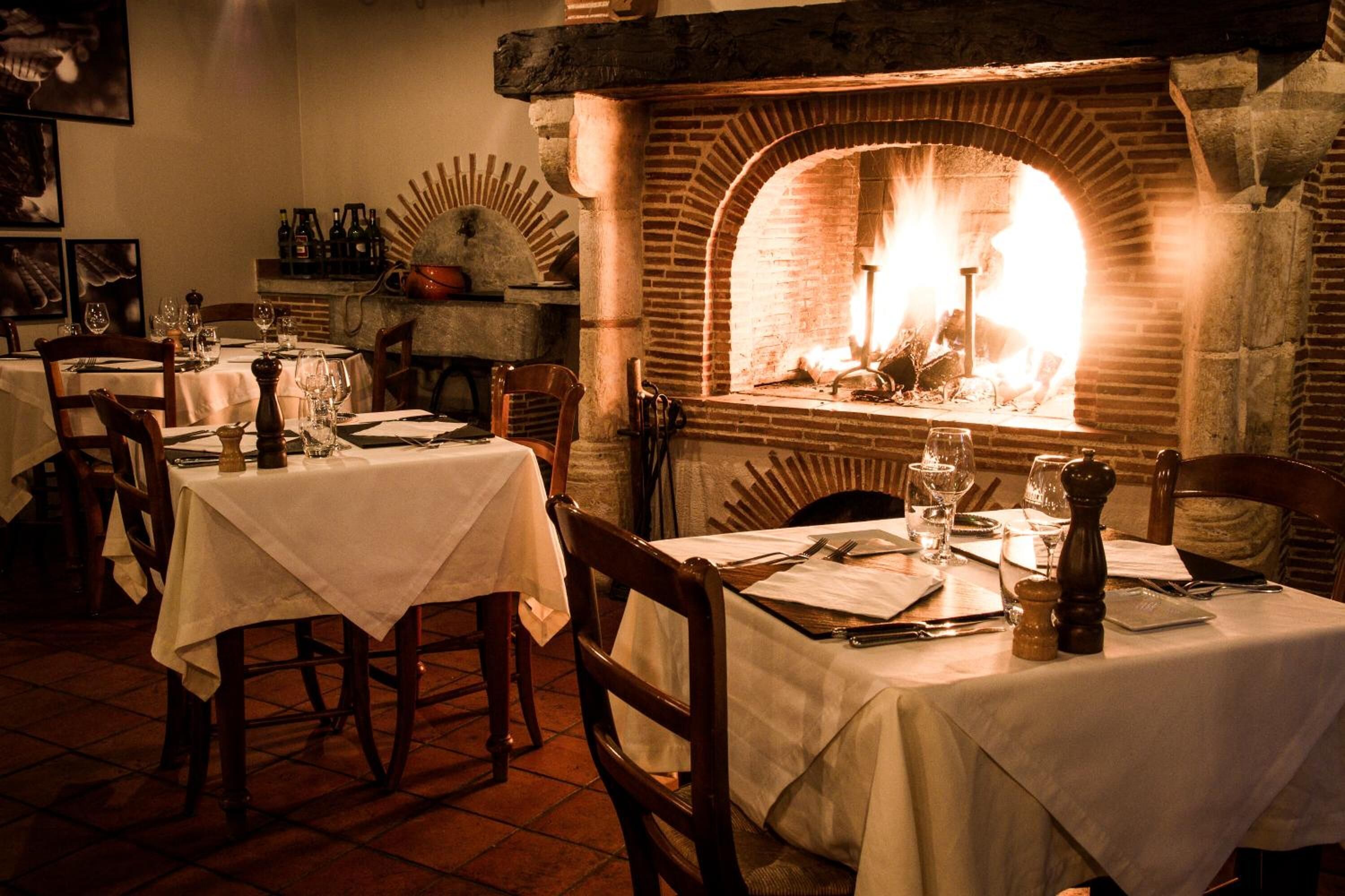 Un restaurante con paredes de ladrillo, chimenea y mesas dispuestas para comer.