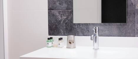 A bathroom with a white sink, a mirror, and toiletries on the counter.