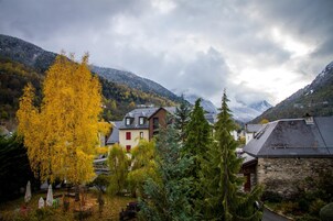 Un pueblo de montaña con casas tradicionales, un llamativo árbol amarillo y un edificio de piedra.