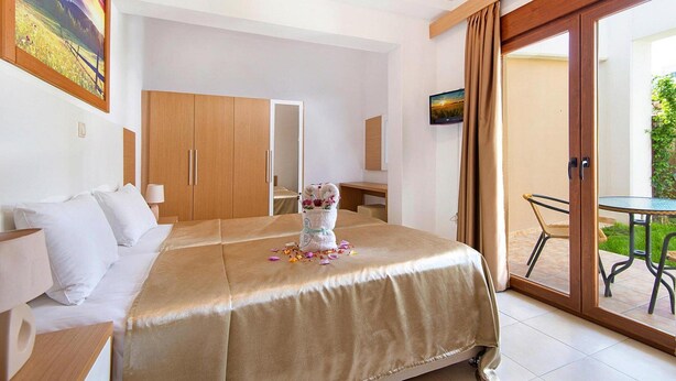 A hotel room with a bed, a desk, a chair, a TV, and a sliding glass door leading to an outdoor area. - Holiday home in Kiotari with a terrace (Kiotari)