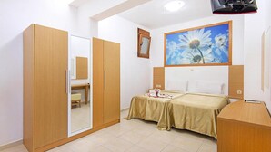 A bedroom with a bed, a wardrobe, a desk, and a painting of a flower. - Holiday home in Kiotari with a terrace (Kiotari)