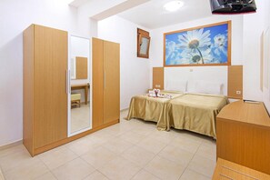 A bedroom with a bed, a wardrobe, a desk, and a painting of a flower.