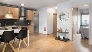 A modern kitchen with wooden cabinets, a stainless steel refrigerator, and a dining area with black chairs. - Downtown Apartment by Old Harbor (Reykjavík)