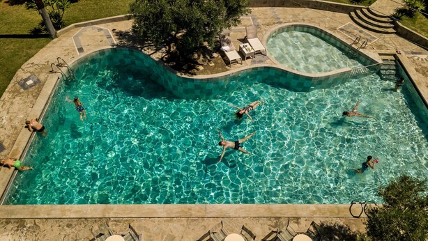 En swimmingpool med flere personer, der svømmer og slapper af.