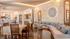 A spacious living area with a dining table, sofas, and a stone accent wall. - Duplex Gerakini Apartment with Pool (Gerakini)