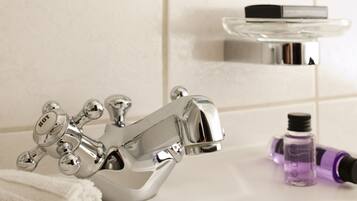 Ein Badezimmer mit chromfarbenem Wasserhahn, einer Seifenspender und einem Handtuch.