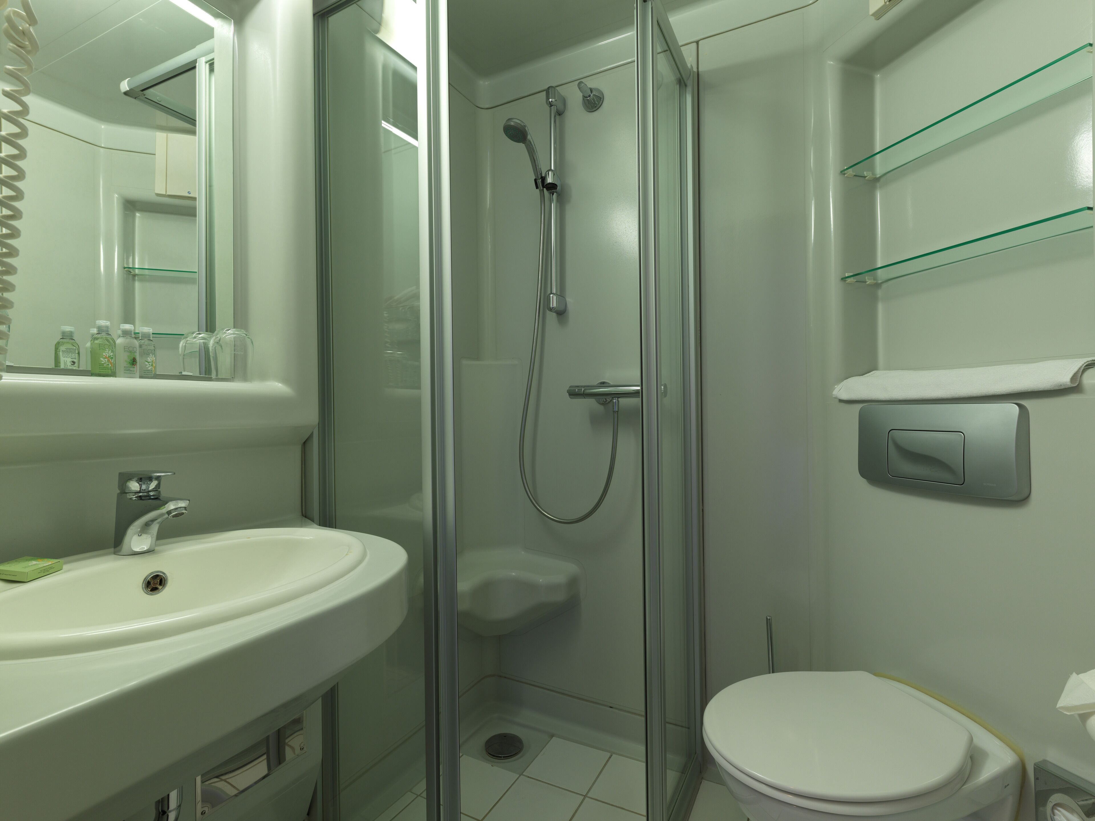 A modern bathroom with a glass-enclosed shower, a white sink, and a toilet.