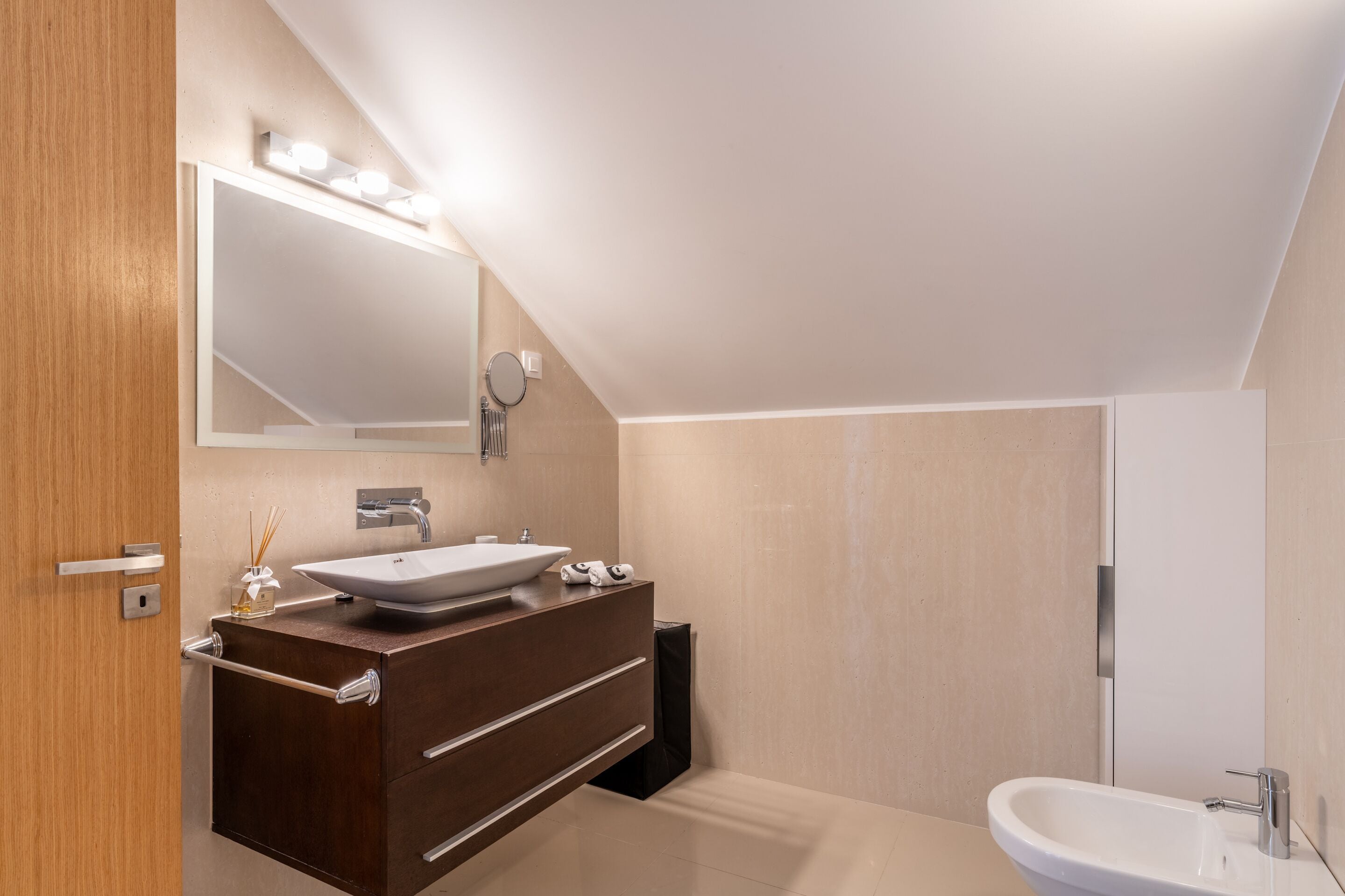 Un baño moderno con un espejo grande, un lavabo sobre encimera y un lavamanos independiente.