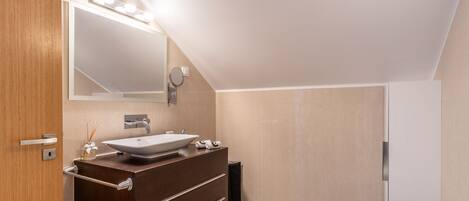 Un baño moderno con un espejo grande, un lavabo sobre encimera y un lavamanos independiente.