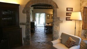 Un interno con pareti in pietra, un caminetto, un'area pranzo e un divano.