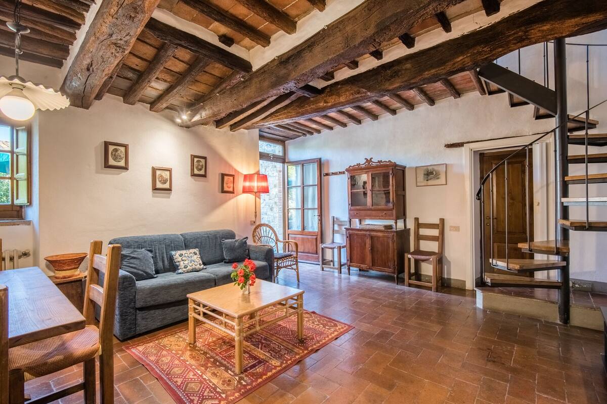 Un amplio salón con techo de madera, un sofá, una mesa de centro y una escalera que sube a un piso superior.