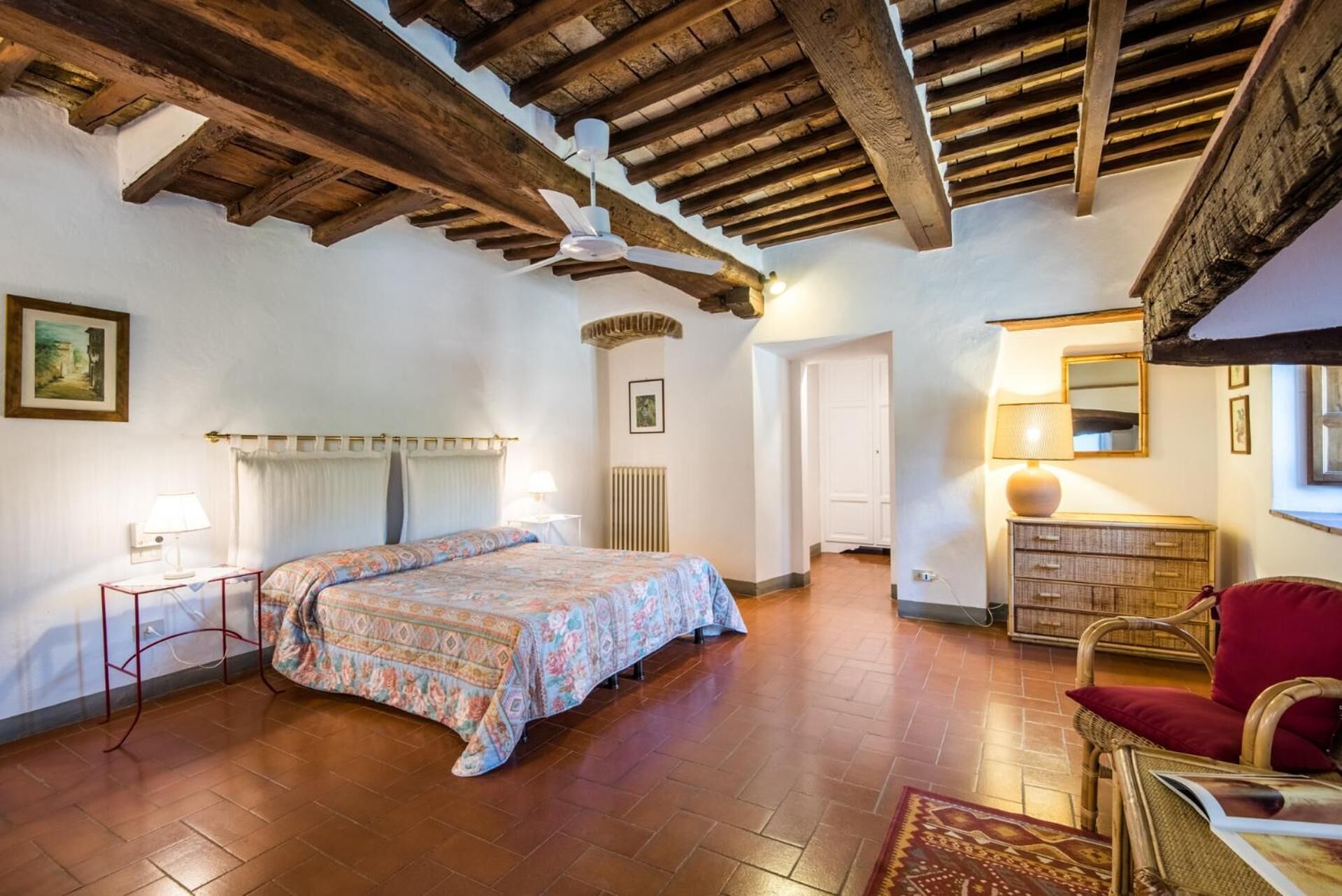 A bedroom with a bed, a chair, a dresser, and a ceiling fan.