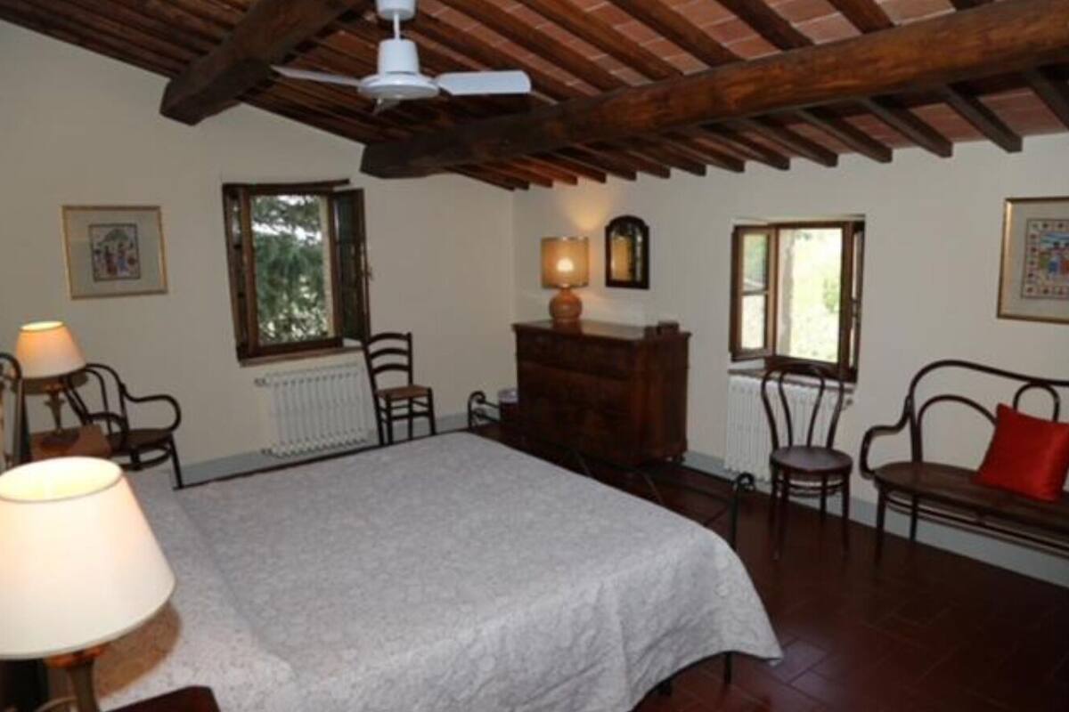 Un dormitorio con cama, vigas de madera en el techo, un radiador, un escritorio, una silla y una ventana.