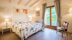 A bedroom with a bed, bedside tables, a chair, and a window with curtains. - Casa Vacanze Squarcialupi (Castellina in Chianti)