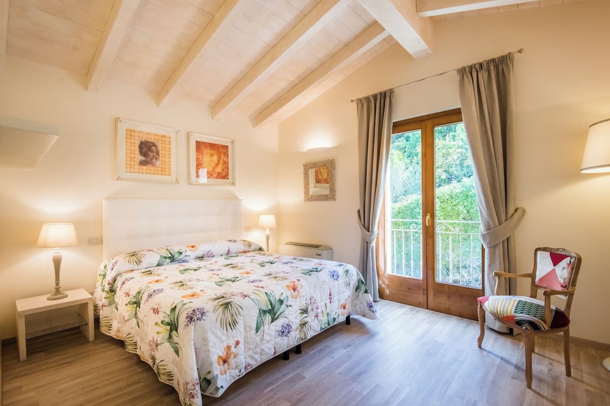 Une chambre à coucher avec un lit, des tables de chevet, une chaise et une fenêtre avec des rideaux.