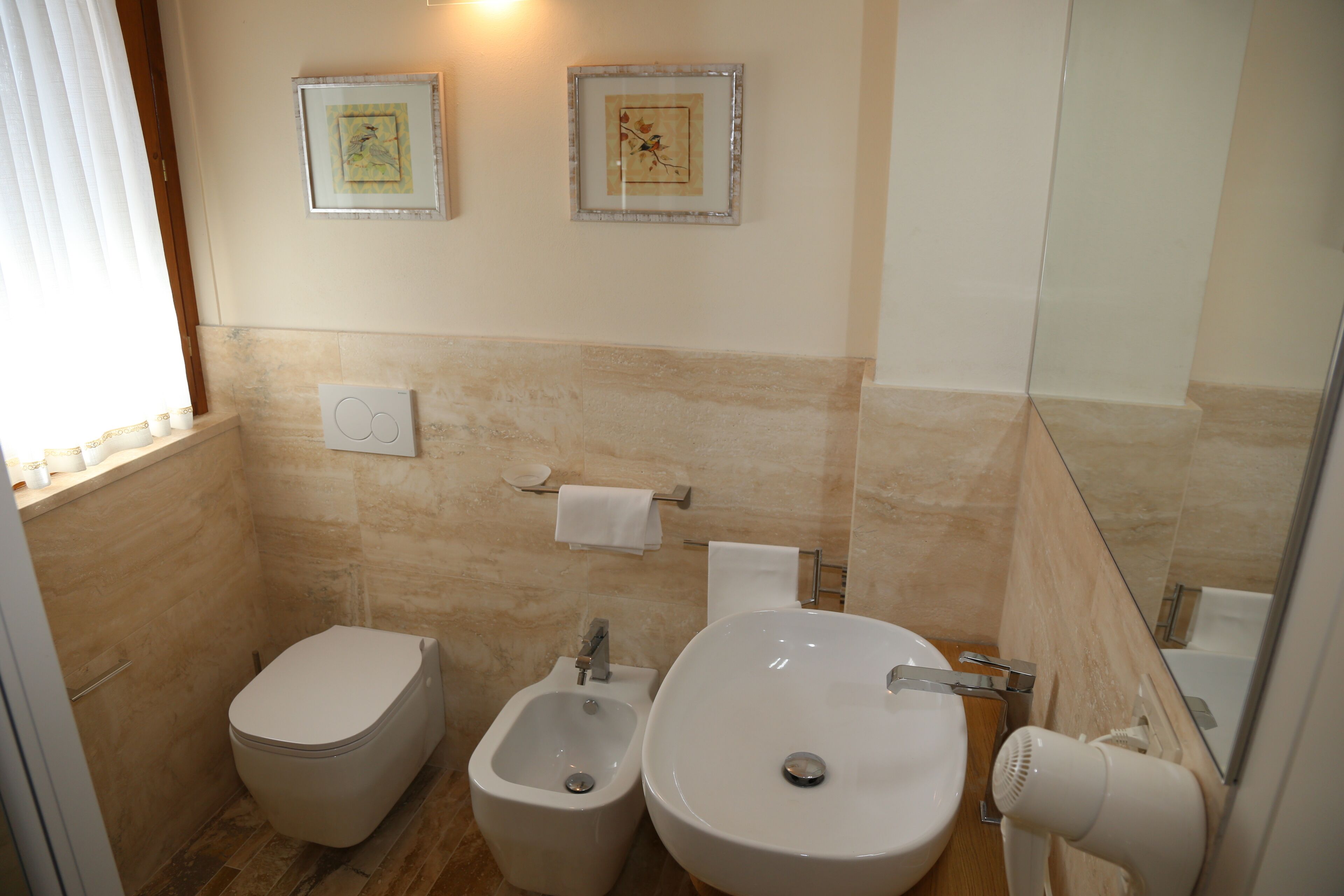 Une salle de bain comprenant des toilettes, un bidet, un lavabo et un porte-serviettes.