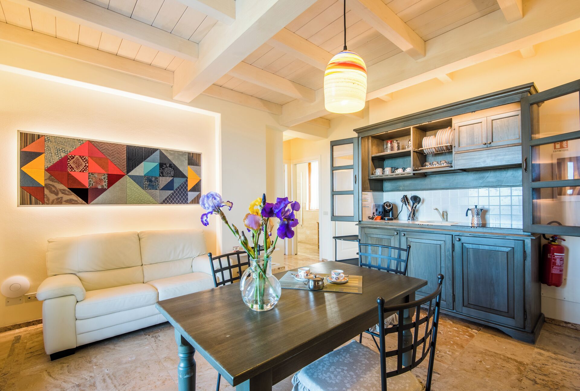 A dining area with a wooden table, chairs, and a vase with flowers.