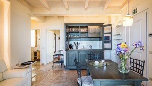 A modern kitchen with dark wooden cabinets, a dining table with chairs, and a vase of flowers on the table. - Casa Vacanze Squarcialupi (Castellina in Chianti)