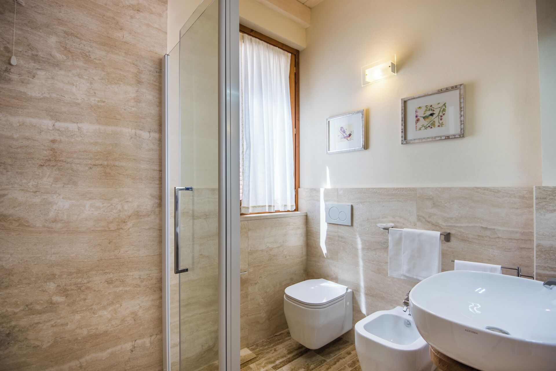 A modern bathroom with a glass shower enclosure, a toilet, bidet, and a large sink with a basin.