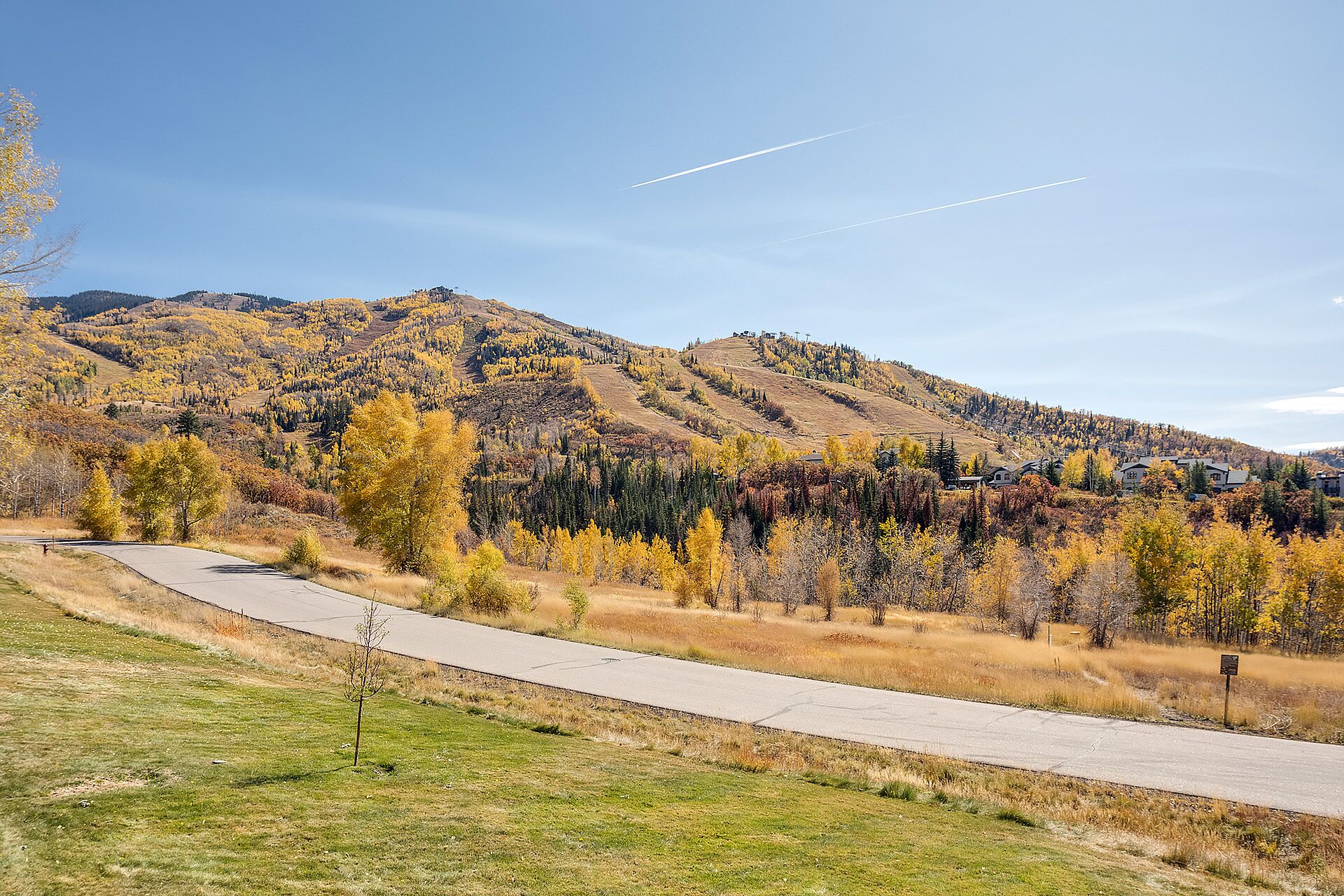 Une route asphaltée qui serpente à travers une région montagneuse aux couleurs automnales.