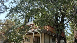 Ein zweistöckiges Haus mit einer Holzterrasse und einer Treppe, die zum oberen Stockwerk führt.