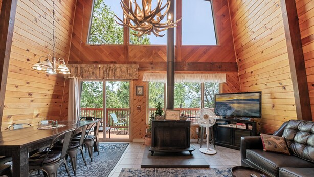 Ein Holzblockhaus-Interieur mit Essbereich, Kamin, Sofa und Fernseher.