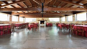 A large hall with wooden beams and a central fireplace, arranged with tables and chairs for dining. - Masseria Spetterrata (Fasano)