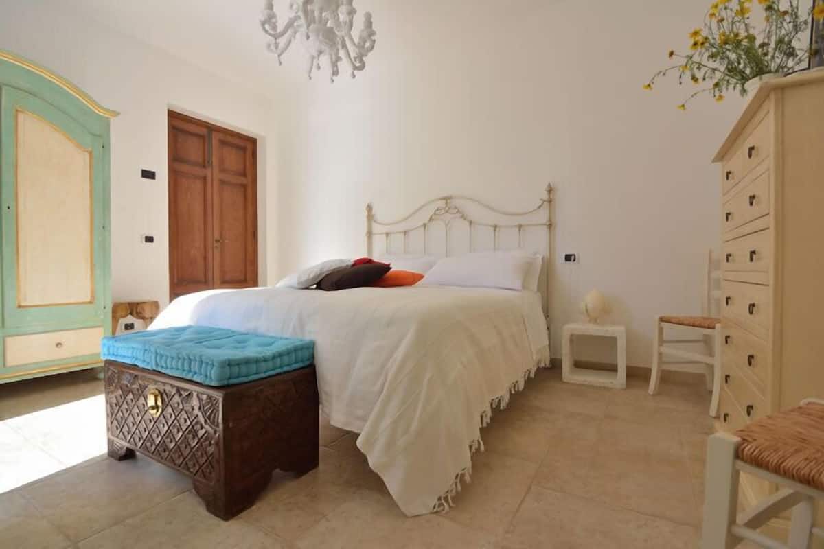 A bedroom with a bed, a dresser, a nightstand, and a small table.