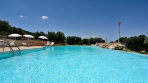 A clear blue pool with lounge chairs and umbrellas. - Masseria Spetterrata (Fasano)