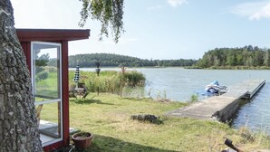 Una cabaña junto al lago con muelle, asientos exteriores y vistas al lago.
