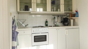 Una cocina con armarios blancos, estufa, lavavajillas y cafetera.