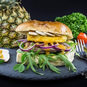 A sandwich with a bun, cheese, meat, and vegetables on a slate plate. - Hotel Gasthof Schäffler (Sonthofen)