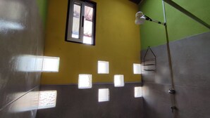 Un baño con varias ventanas pequeñas, zona de ducha y un perchero para toallas.
