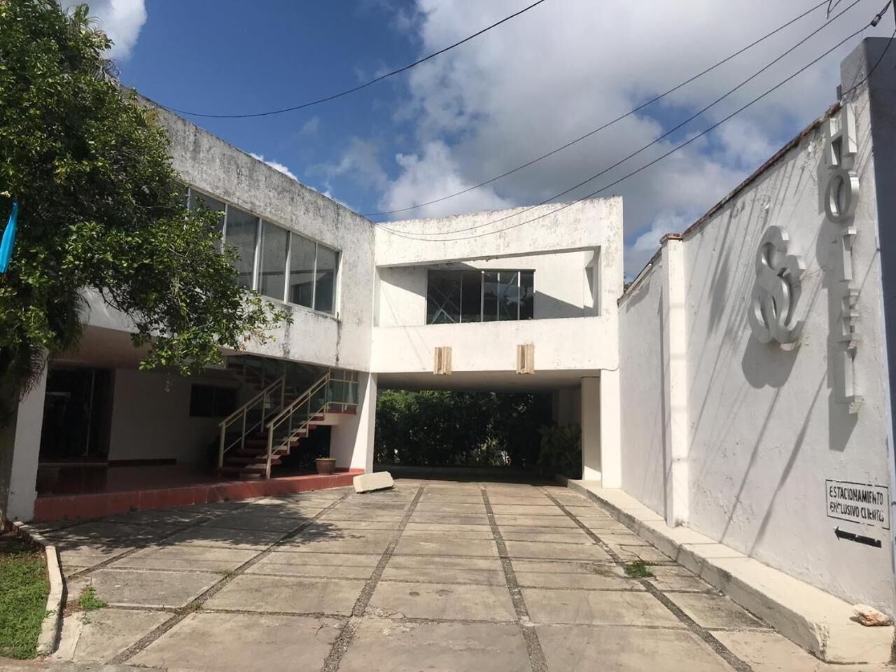 Un edificio de dos plantas con un patio central, una escalera y una zona cubierta.