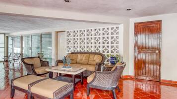 A room with a sofa, two armchairs, a coffee table, and a decorative wall panel.