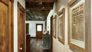 A hallway with wooden doors, framed historical documents on the walls, and a wooden floor. - Entire Home at Melissa's Farmstead (Fredericksburg)