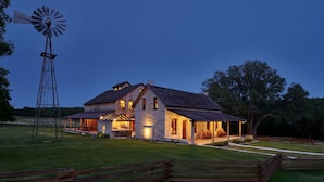A large house with a windmill, a covered porch, and a well-maintained lawn. - Entire Home at Melissa's Farmstead (Fredericksburg)