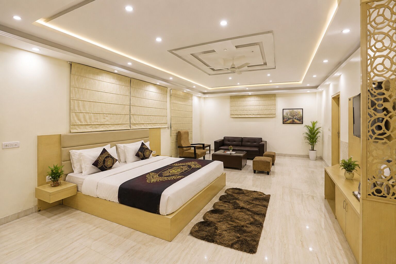 Une chambre d’hôtel moderne avec un grand lit, un canapé, une table basse et un élément de séparation décoratif.