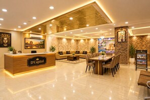 Un vestíbulo de hotel con mostrador de recepción, zona de estar y una mesa de comedor.