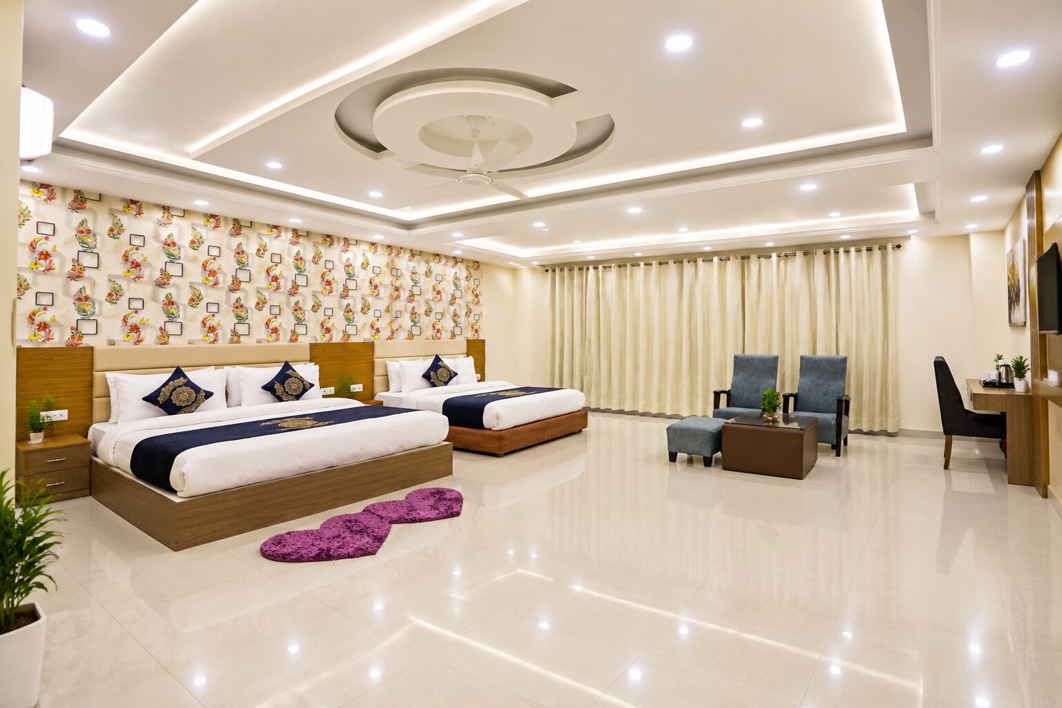 A modern hotel room with two beds, a desk, and a seating area.