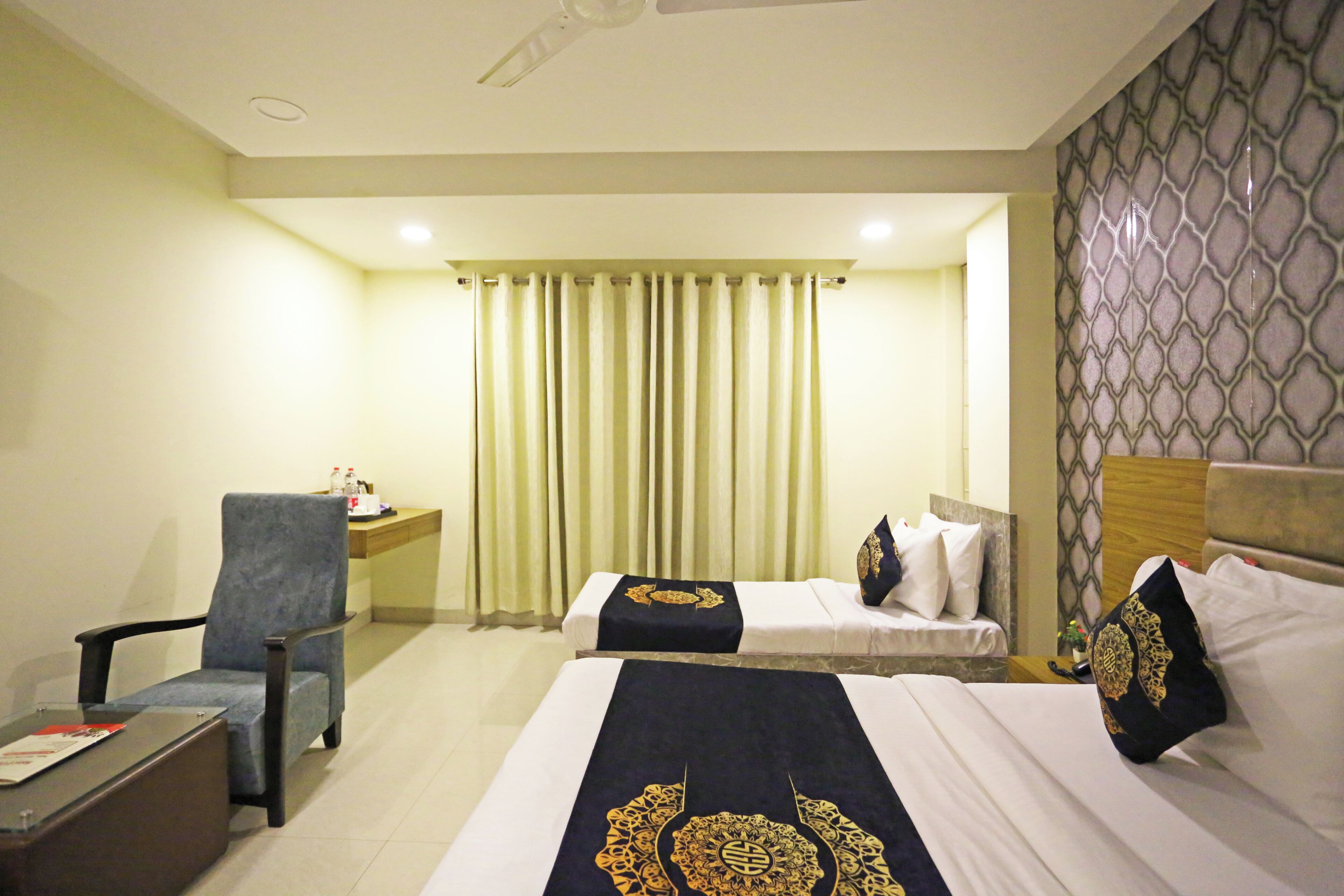 A hotel room with two beds, a desk, a chair, and a curtain.