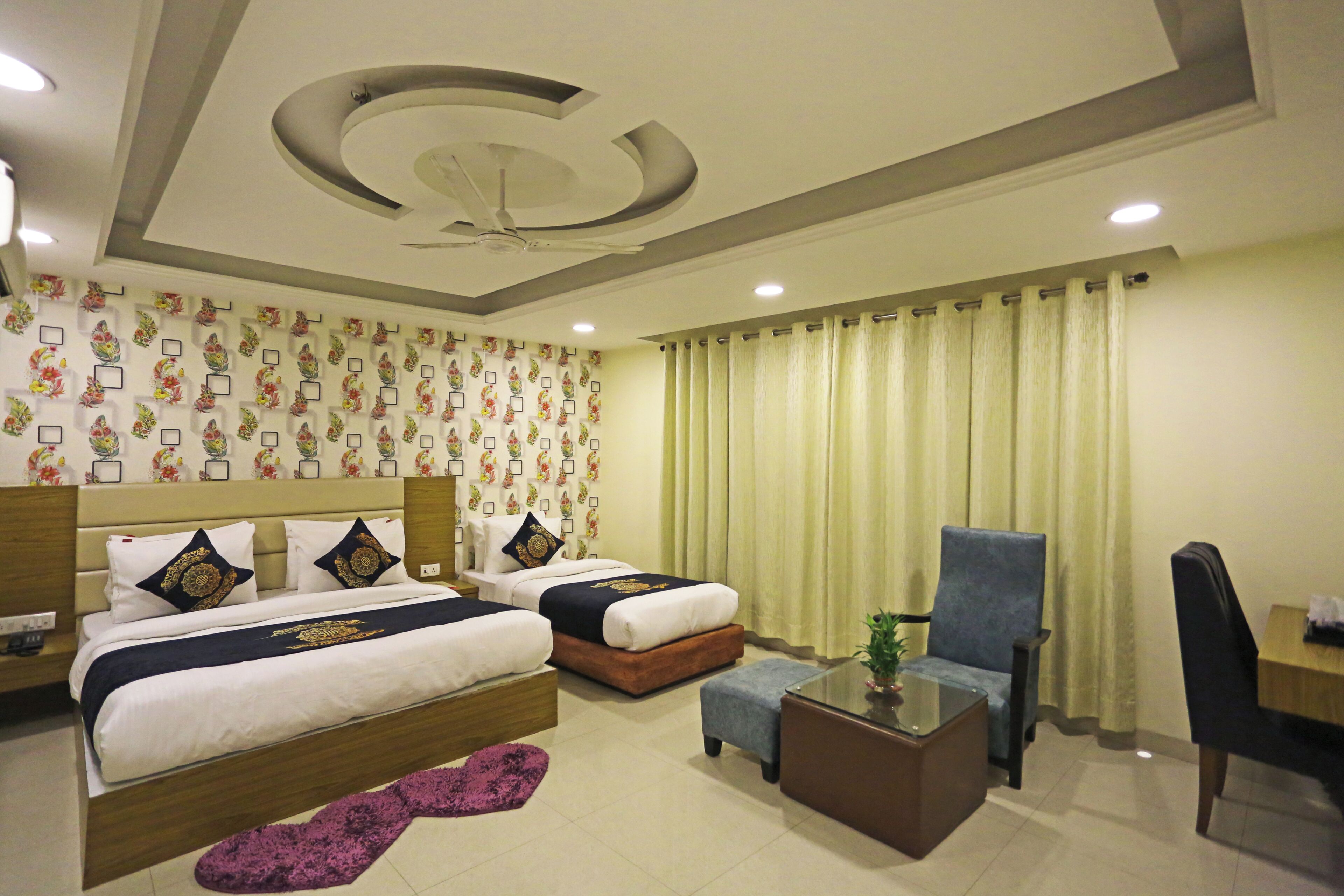 A hotel room with two beds, a coffee table, a chair, and a desk.