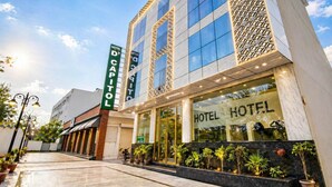 A hotel with a prominent 'HOTEL' sign, a modern facade with large windows, and a well-maintained entrance area with potted plants. - The D'Capitol Delhi, International Airport (New Delhi)