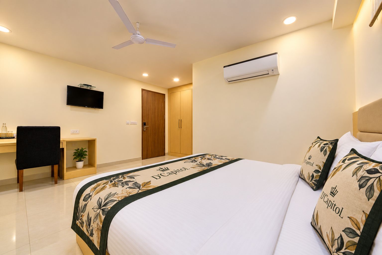 A bedroom with a bed, a desk, a chair, a television, and an air conditioning unit.