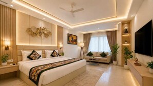 A modern bedroom with a large bed, a sofa, a TV, and a ceiling fan. - The D'Capitol Delhi, International Airport (New Delhi)
